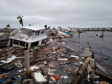 Hurricane debris such as a sunken vessel and lumber, floats in the water.